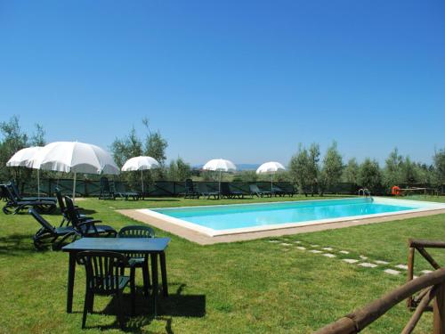 a pool with chairs and a table in the grass at Rustic style flat with swimming pool in Guistrigona