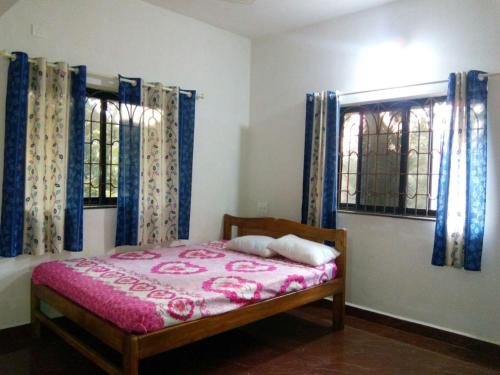 een slaapkamer met een bed en twee ramen bij Nhanji House in Arambol