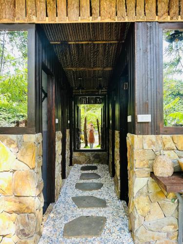 a stone walkway with a person walking through a building at Zenda Glamping in Bao Loc
