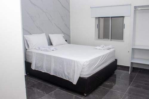 a bedroom with a bed with white sheets and pillows at Hotel Mall plaza in Santa Marta