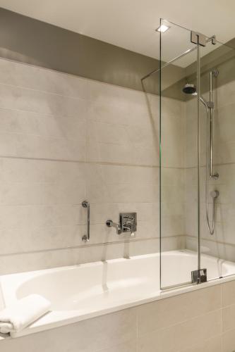 a bathroom with a bath tub with a shower at Hotel Alma Am Anger in Erfurt