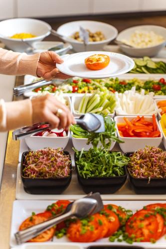 a buffet filled with plates of food and bowls of vegetables at Hotel Dom Zdrojowy Resort & SPA - Destigo Hotels in Jastarnia