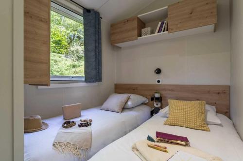 une chambre avec deux lits et une fenêtre dans l'établissement Camping 4 étoiles - Piscine - eeieab, à Castelnaud-la-Chapelle