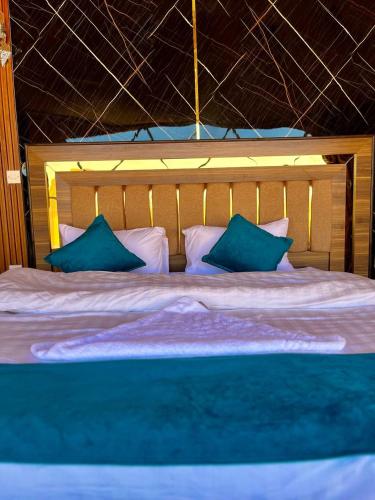 a bedroom with a large bed with blue pillows at Rum Angel Camp in Wadi Rum