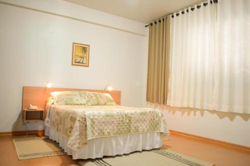 a bedroom with a bed and a large window at Pampa Hotel in Vacaria