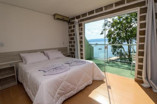 a bedroom with a bed and a large window at Pousada Praia da Lagoinha in Bombinhas