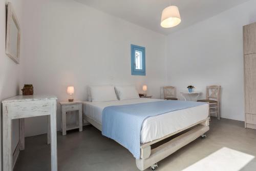 a white bedroom with a bed and two tables at Ammos Studios in Donoussa
