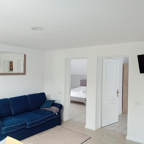 a living room with a blue couch and a bedroom at Casa Mont Blanc Cavnic apartament 2 in Cavnic