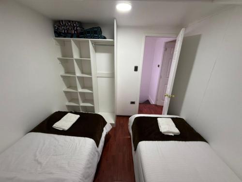 two beds in a small room with white walls at Cabañas Última Esperanza in Puerto Natales