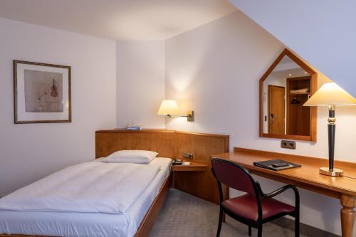 a bedroom with a bed and a desk and a chair at Hotel Alma Am Anger in Erfurt