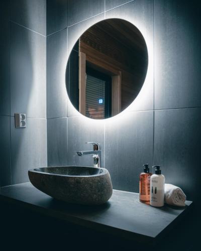 a bathroom with a sink and a round mirror at Sky Lodging ~ sleeping under the stars in Rovaniemi