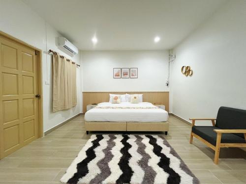 a bedroom with a bed and a chair and a door at Sleeping Shine by DeliZia Satun พักได้ 8-9 ท่าน in Satun