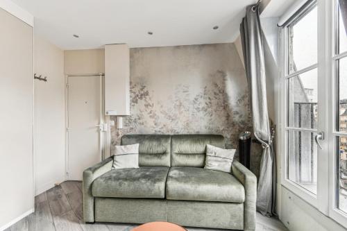 a living room with a green couch in front of a wall at Studio Mac Mahon - Champs Elysees in Paris