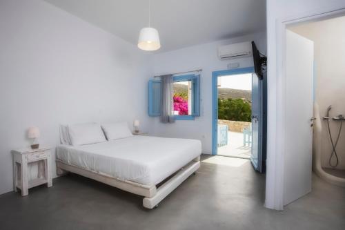 a white bedroom with a bed and a window at Ammos Studios in Donoussa