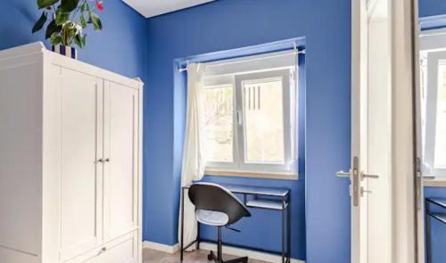 a blue room with a chair and a window at Refreshed apartment with private garden in Almada