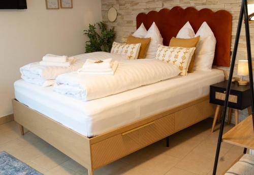 een groot bed met witte lakens en kussens erop bij Würzburg Studio mit Dachterrasse - Tiefgarage & Nähe Bahnhof in Würzburg