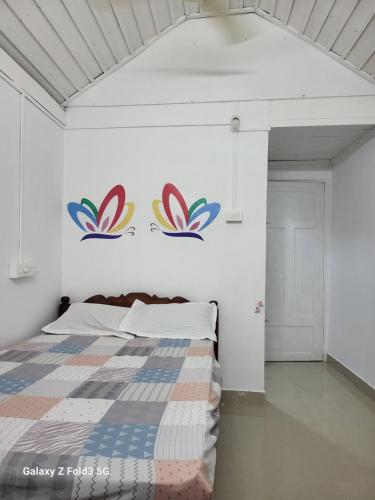 a bedroom with a bed with colorful decals on the wall at Emma Homestay in Pattiyūrgrāmam
