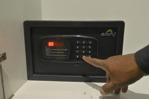 a hand pointing at the clock on a microwave at Hotel JK palace in Allahābād