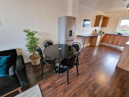 a living room with a table and chairs and a kitchen at Lovely 3 Bed Close to Centre by City SuperHost in Manchester