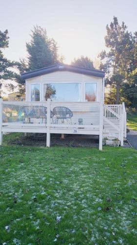 a white fence with a gazebo in the grass at Caravan under the tree in Port Seton