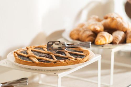 una torta su un piatto bianco su un tavolo con pasticcini di Hotel Ondina e Milazzo a Cervia