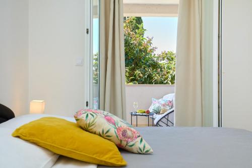 a bed with a yellow pillow and a window at Apartment Summer Chill 1 in Trsteno