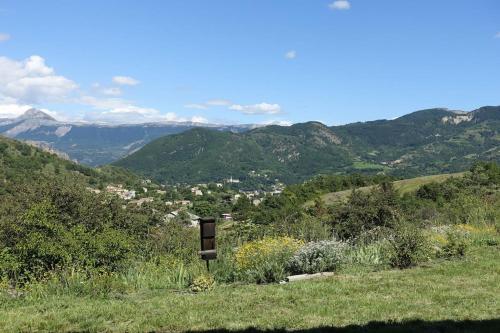 a sign on a hill with mountains in the background at Gîte Provence Pure Nature in Digne-les-Bains