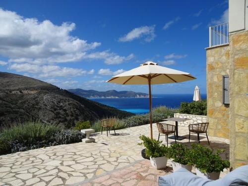 a patio with a table and an umbrella at Myrtos Bay Apartments in Anomeriá
