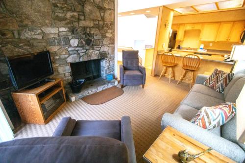 a living room with a couch and a stone fireplace at Fox Run at Lake Lure in Lake Lure