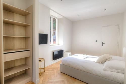 une chambre blanche avec un lit et une télévision dans l'établissement Joli appartement T2, bien équipé, Saint-Didier, à Saint-Didier-au-Mont-dʼOr