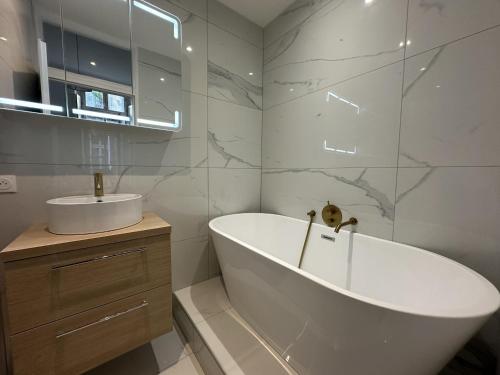 une salle de bain blanche avec une baignoire et un lavabo dans l'établissement Rolland, à Bordeaux