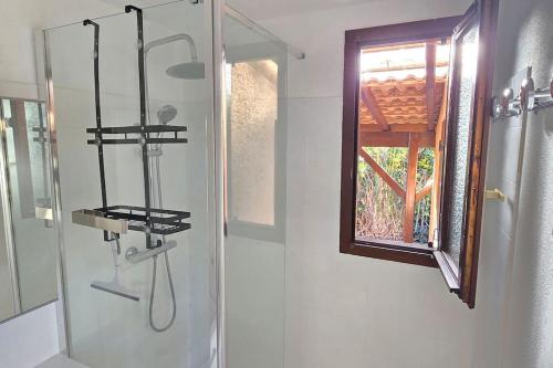 une salle de bain avec une douche avec pommeau de douche dans l'établissement Maison dans résidence, piscines, proximité plage, à Vendres
