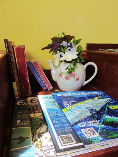 a table with a book and a vase with flowers at Miller's Guest House in Buccoo