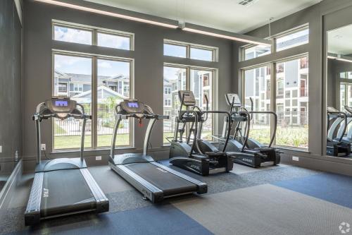 a gym with several tread machines in a room with windows at Cullen 8206 I New Construction 1bd Apt I Gated in Houston