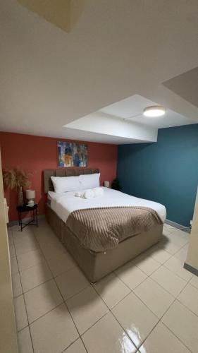 a bedroom with a large bed with a blue wall at Large Studio for Contractors, Families, Relocation Near New Cross Hospital in Monmore Green