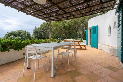 a patio with a white table and chairs under a pergola at Dimora Punta Rossa in San Felice Circeo