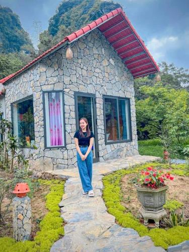 a woman standing in front of a small house at Trang an green river homestay in Ninh Binh