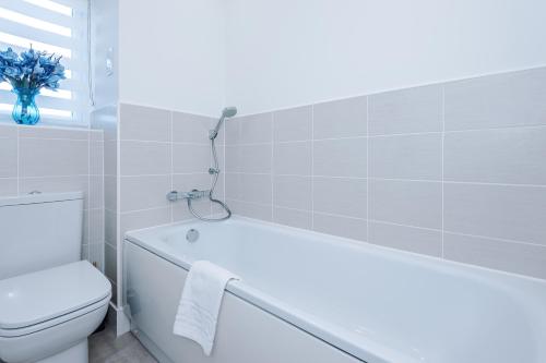 a bathroom with a white tub and a toilet at Hasting's House by YourStays - 3 Bedroom House in Stoke-on-Trent in Stoke on Trent