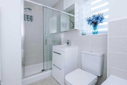 a white bathroom with a toilet and a shower at Hasting's House by YourStays - 3 Bedroom House in Stoke-on-Trent in Stoke on Trent