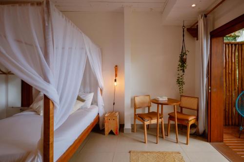 a bedroom with a bed and a table and chairs at Villa Estrela Bungalow in Itacaré