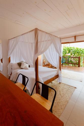 a bedroom with two beds and a table and a window at Villa Estrela Bungalow in Itacaré