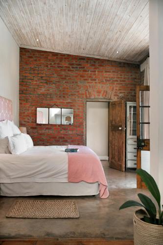 a bedroom with a bed and a brick wall at Dalmore Guest Farm in Bergville