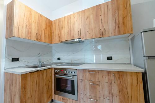 a kitchen with wooden cabinets and a sink at Kotarja Apartments in Dhërmi