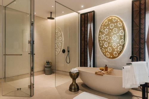 a bathroom with a bath tub and a shower at Our Habitas Ras Abrouq in Dukhān