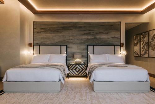 a bedroom with two beds and a large wall at Our Habitas Ras Abrouq in Dukhān