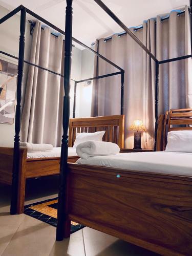 a bedroom with two beds and a canopy bed at Jacomo Residences in Dar es Salaam