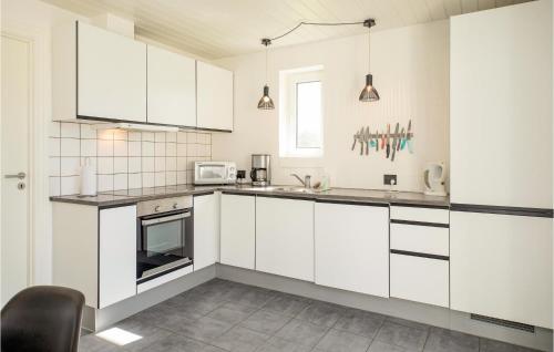 a white kitchen with white cabinets and appliances at Nice Home In Blokhus With Sauna in Blokhus