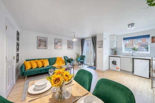 a living room with a green couch and a table at Luxury 5 Bed House - Free Parking - Perfect For Contractors & Families in Welwyn Garden City