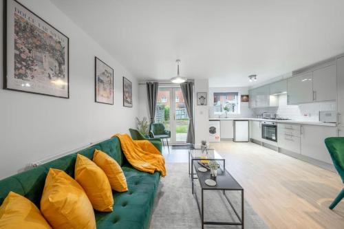 a living room with a green couch and a table at Luxury 5 Bed House - Free Parking - Perfect For Contractors & Families in Welwyn Garden City