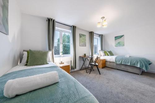 a bedroom with two beds and a desk and windows at Luxury 5 Bed House - Free Parking - Perfect For Contractors & Families in Welwyn Garden City
